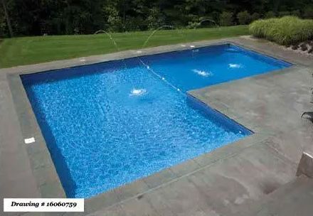 An L-shaped swimming pool with blue water and water fountains, surrounded by a gray stone patio and green lawn.