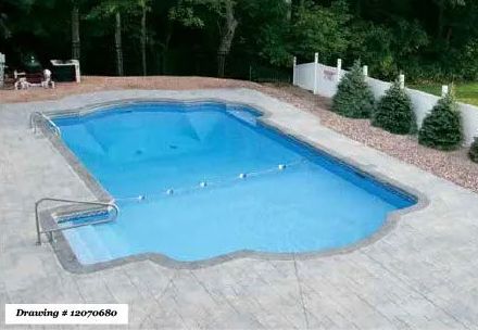 A rectangular backyard swimming pool with a shallow-end staircase, surrounded by a grey textured concrete patio.