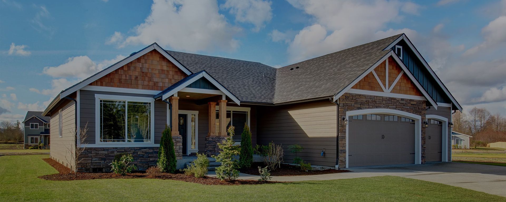 A single-story suburban house with stone and shingle siding, a gray shingled roof, and a three-car garage.