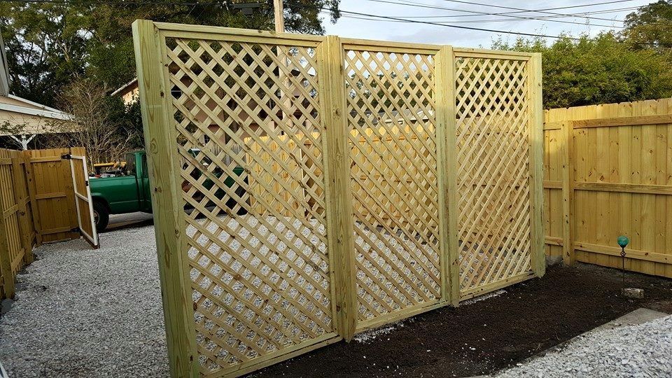 A wooden lattice fence with a gate in a backyard.