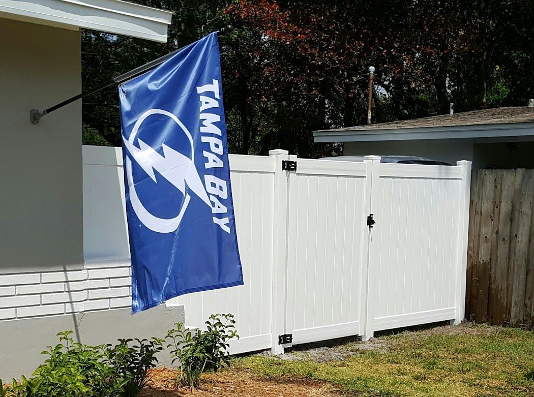 A blue tampa bay flag is flying in front of a white fence