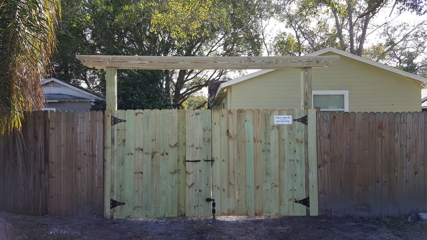 A wooden fence with a gate in front of a house.