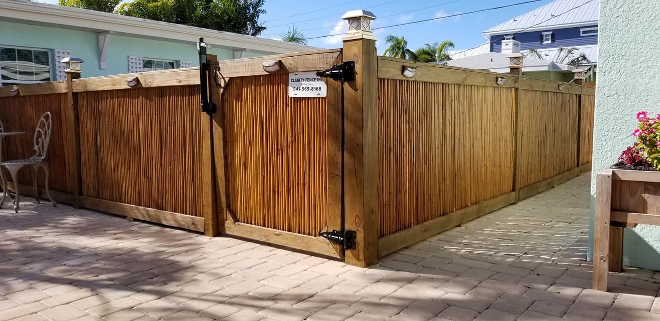 A wooden fence with a gate is surrounded by a brick walkway.
