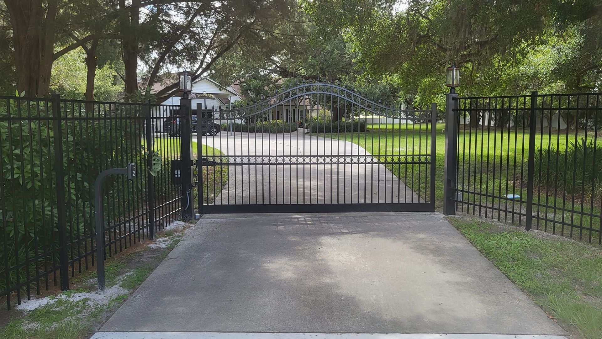 A driveway with a gate and a fence leading to a house.