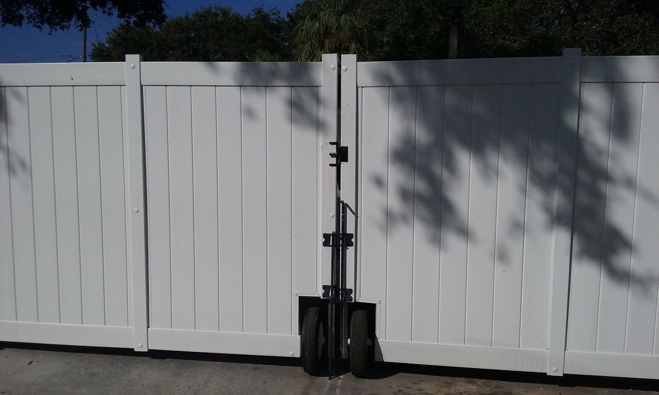 A white fence with a black shovel leaning against it.