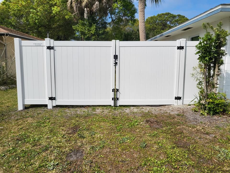 A white fence is sitting in the grass in front of a house.