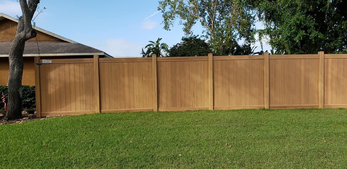 A wooden fence surrounds a lush green lawn in front of a house.