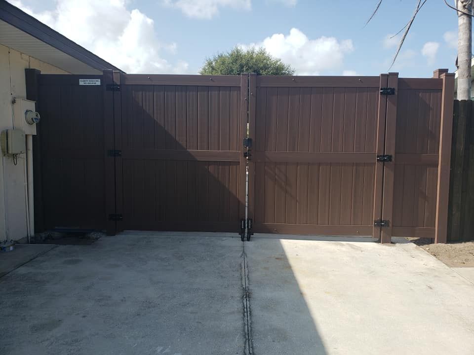 A brown wooden gate is sitting in front of a house.