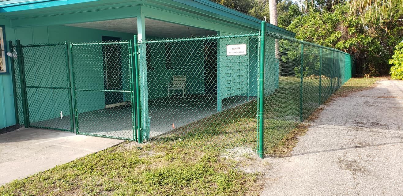 A green chain link fence is surrounding a blue house.