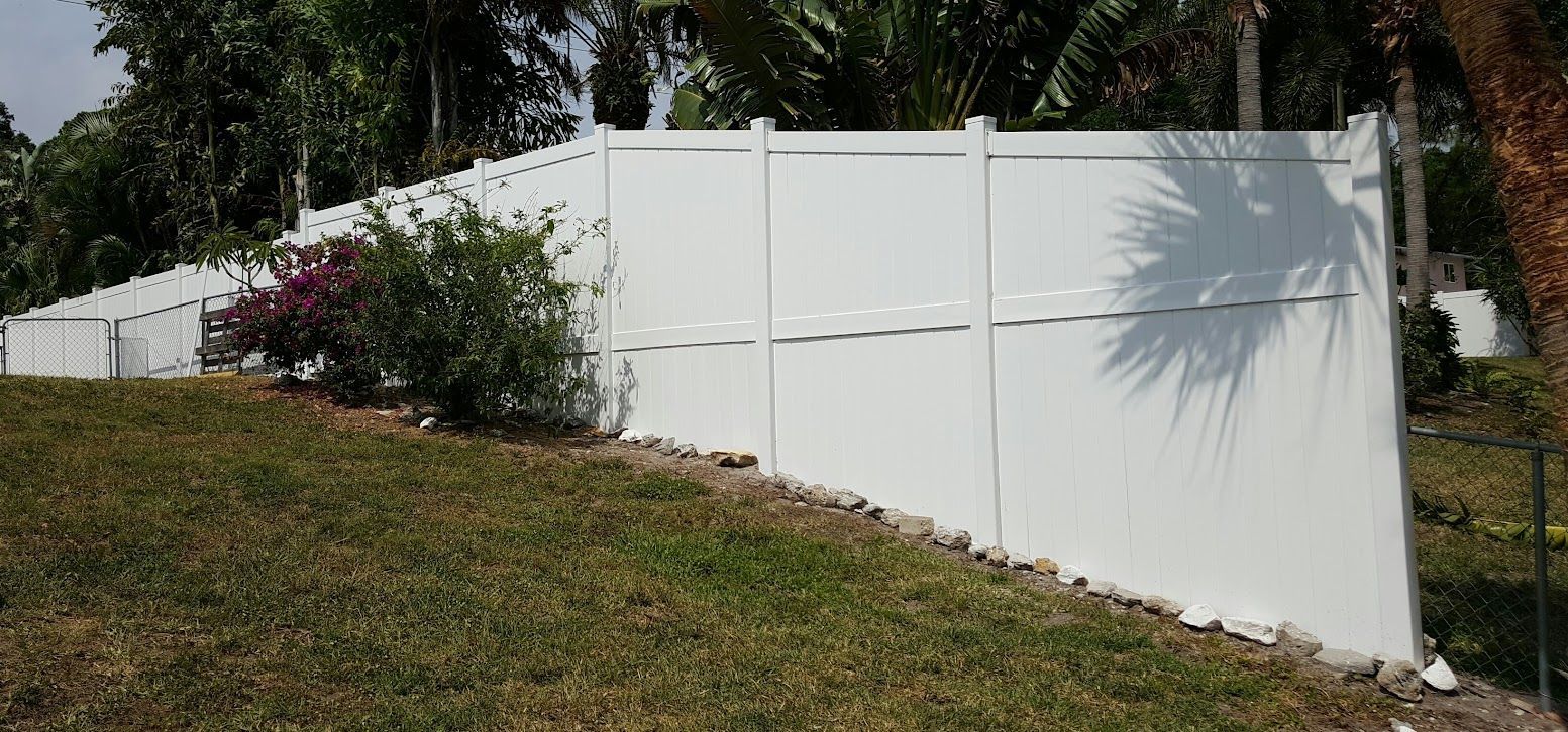 A white fence is sitting on top of a grassy hill.