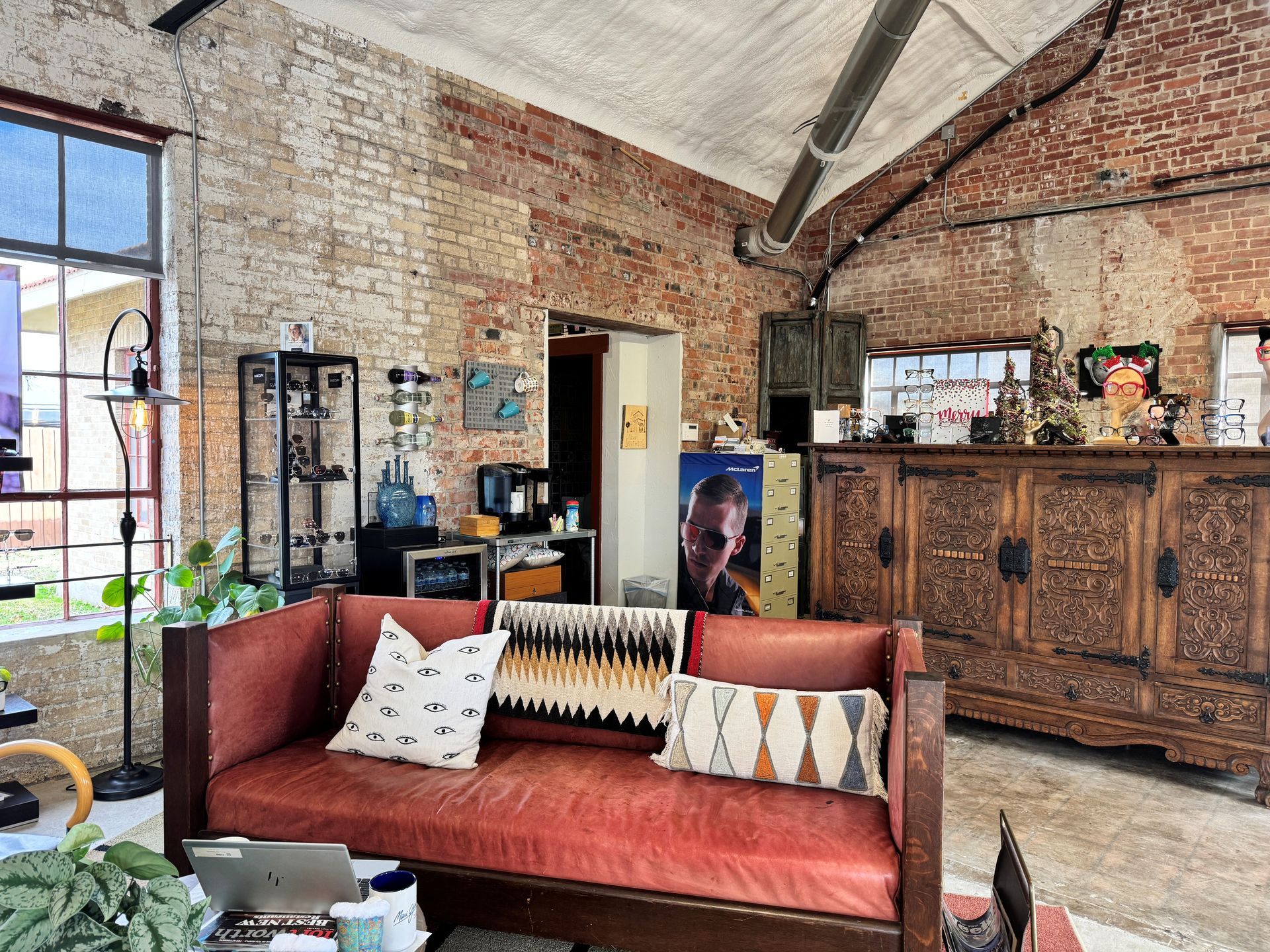 Red leather sofa in a room with exposed brick walls, antique cabinet, and various objects.