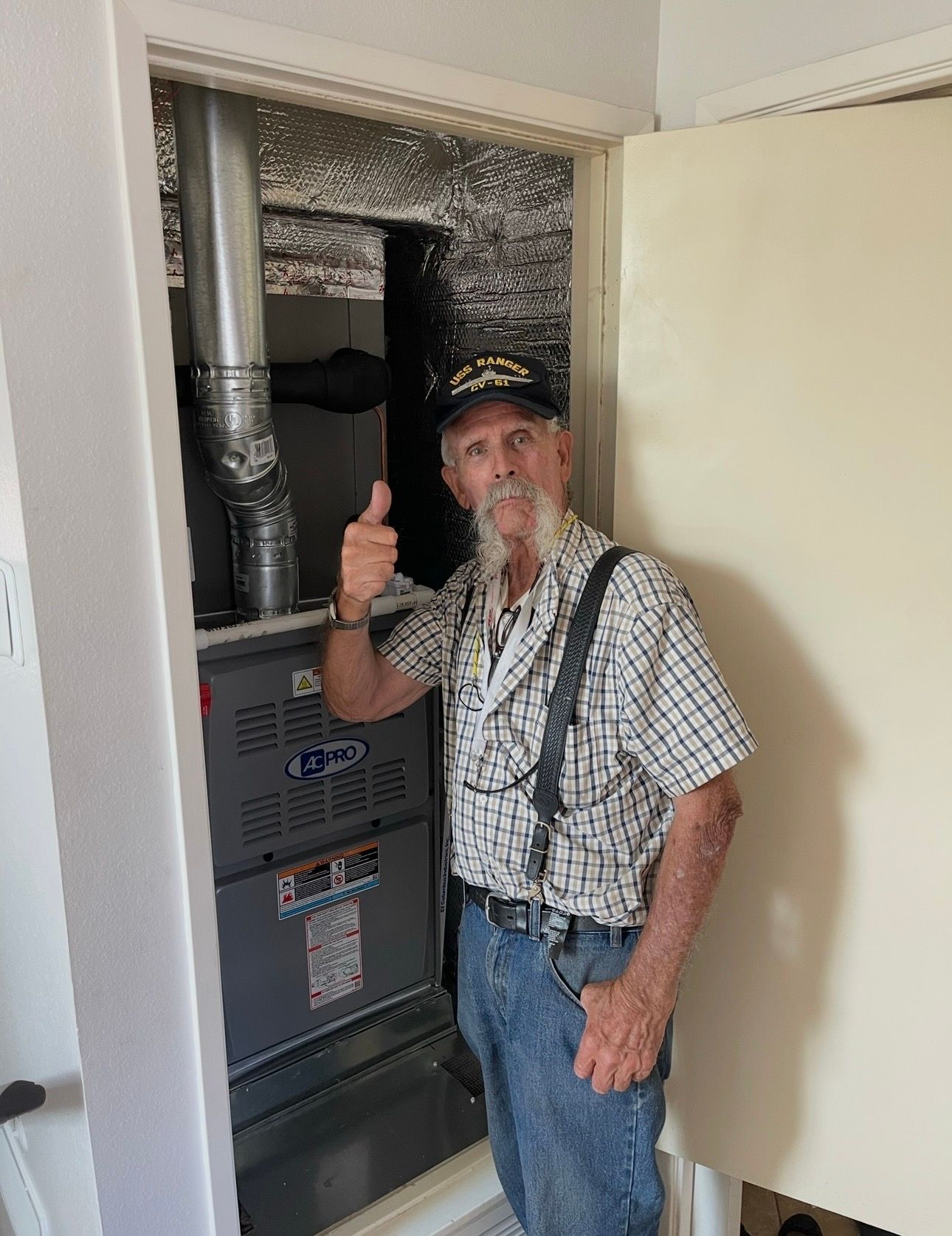 Man giving thumbs-up next to installed furnace unit in a utility room.