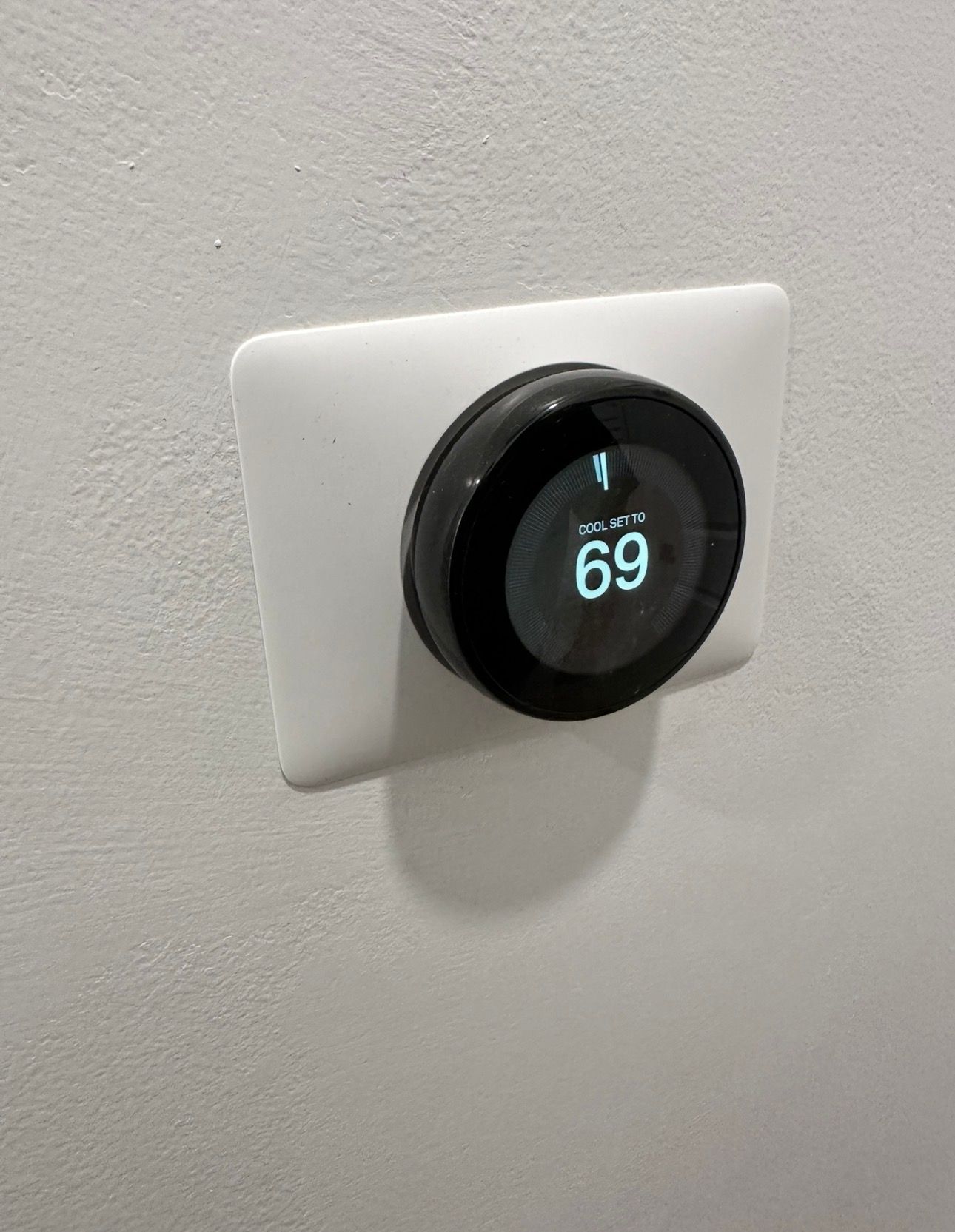A round, black thermostat with a digital display showing 