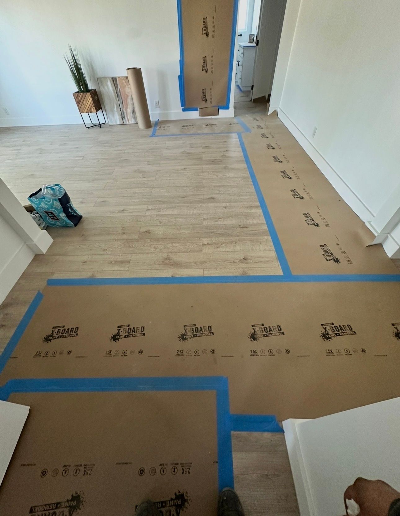 Interior room with cardboard floor protection taped with blue tape, preparing for flooring installation.