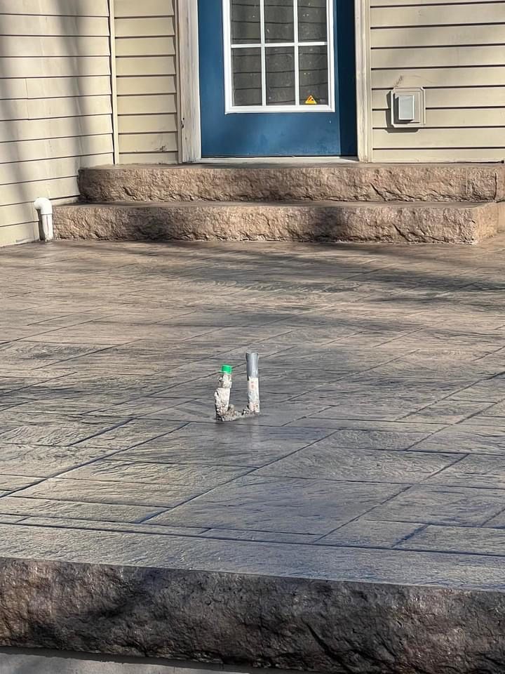 a concrete patio in front of a house with steps and a blue door .
