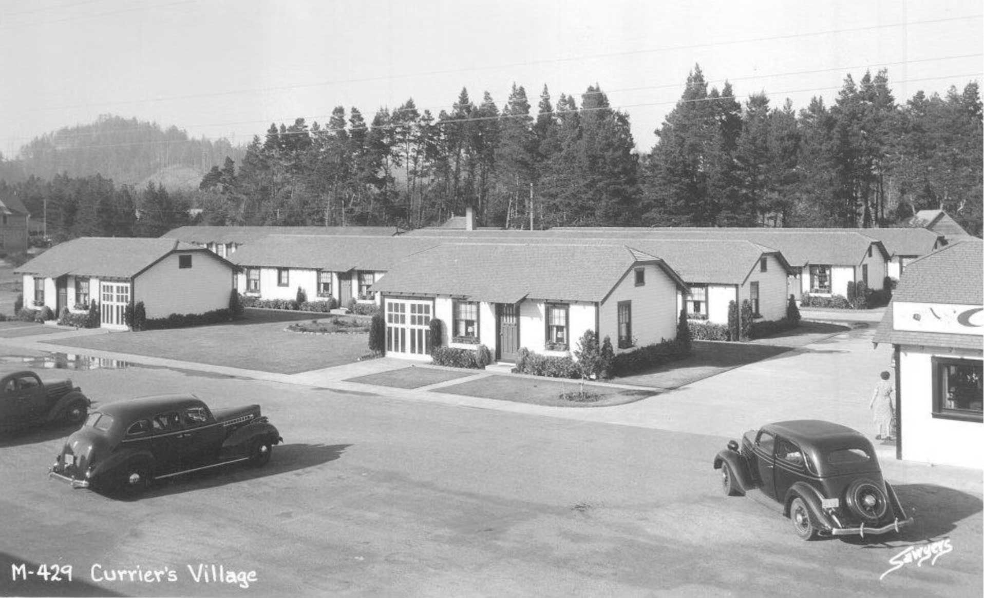a row of small, white houses with parked cars on a street