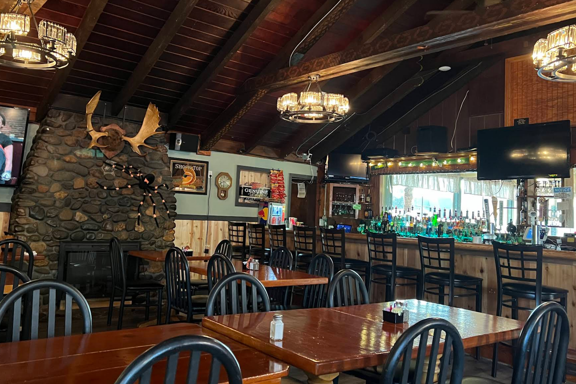 Interior of a rustic bar and restaurant with a stone fireplace and wooden tables and bar.