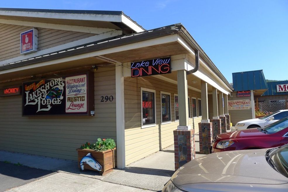 Exterior view of Lakeside Lodge and Cozy Inn, tan buildings with signs, cars parked in front.