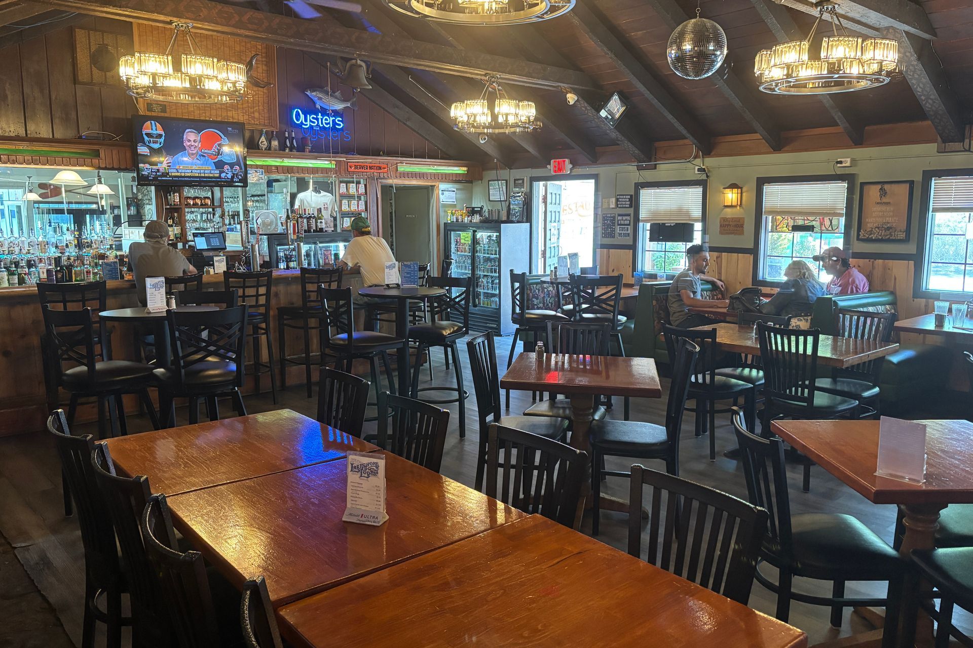 Interior of a bar with tables and chairs; people are seated at tables and the bar.