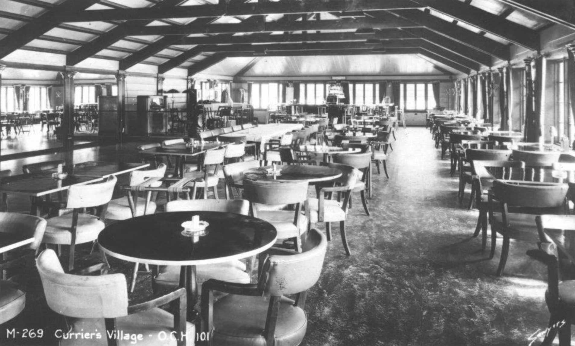 interior of a dining hall with tables, chairs, and sunlight streaming through windows