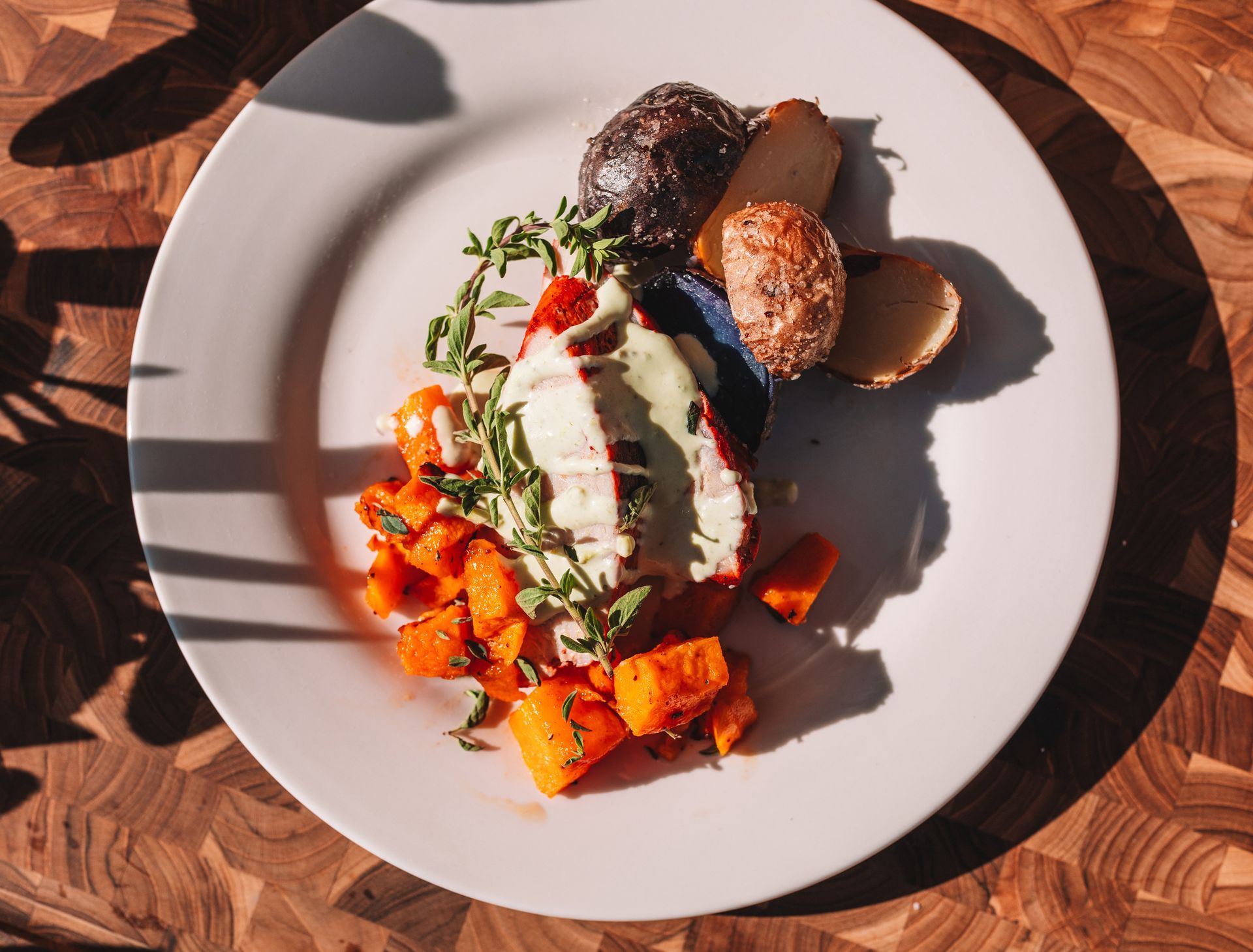 Plate of roasted vegetables with sauce, on a wooden surface.