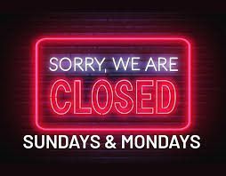 Neon sign, Sorry, We Are Closed with Sundays & Mondays below, in red and white against a black background.