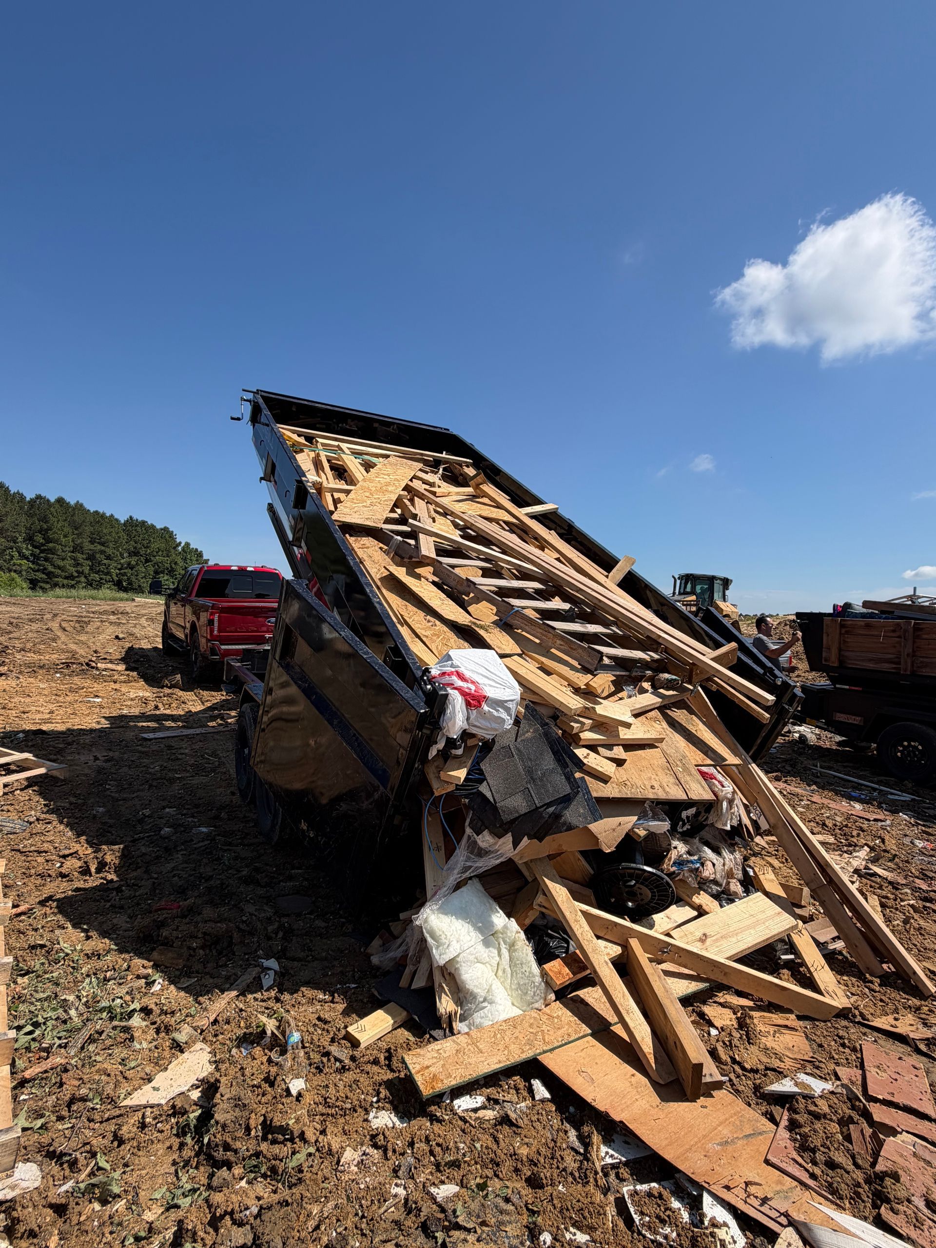 Collapsed roof debris at a construction site under a blue sky, with a red truck nearby.