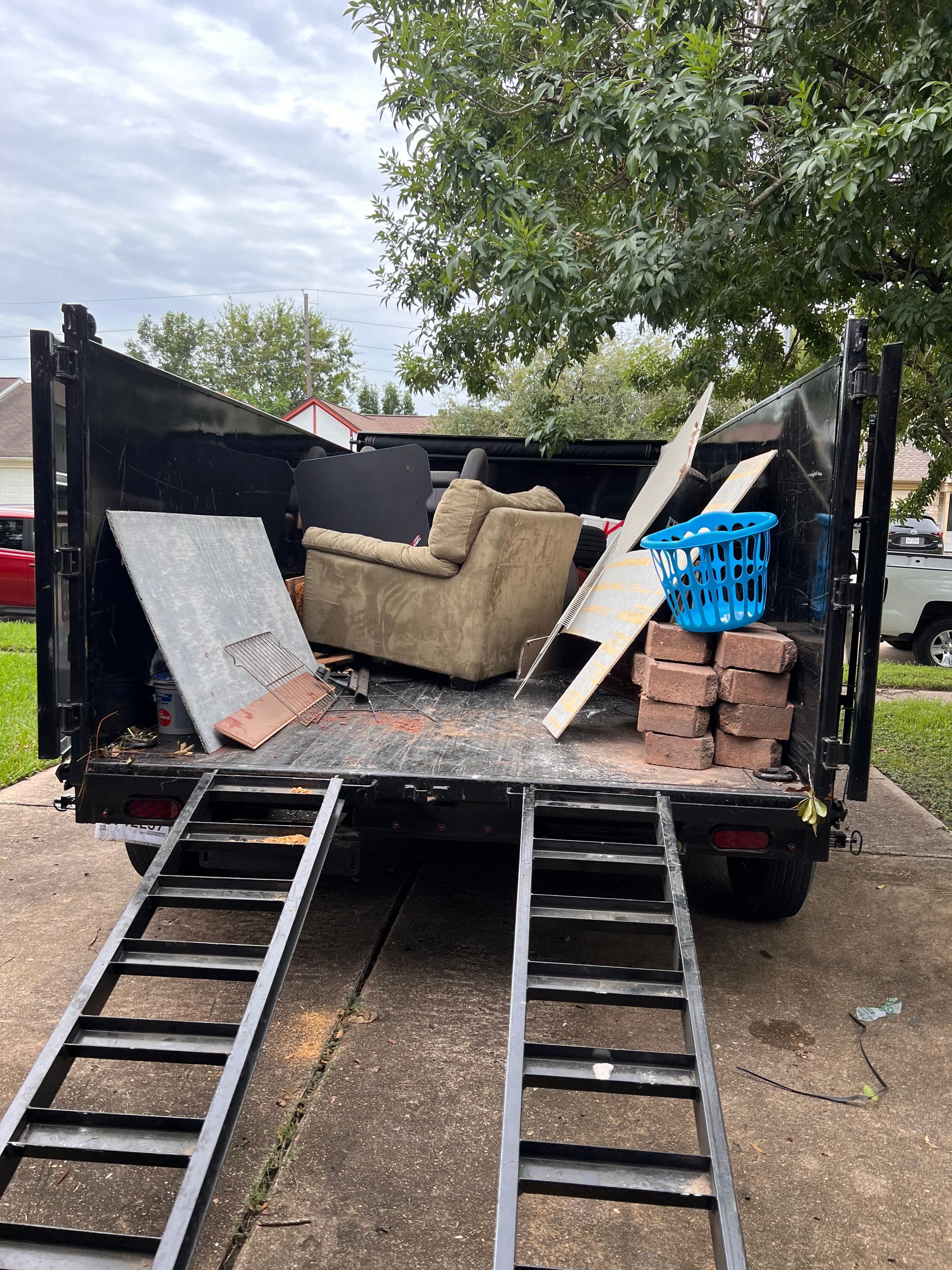 Loading truck with sofa, mattress, blue crate, and ladders extended from the tailgate
