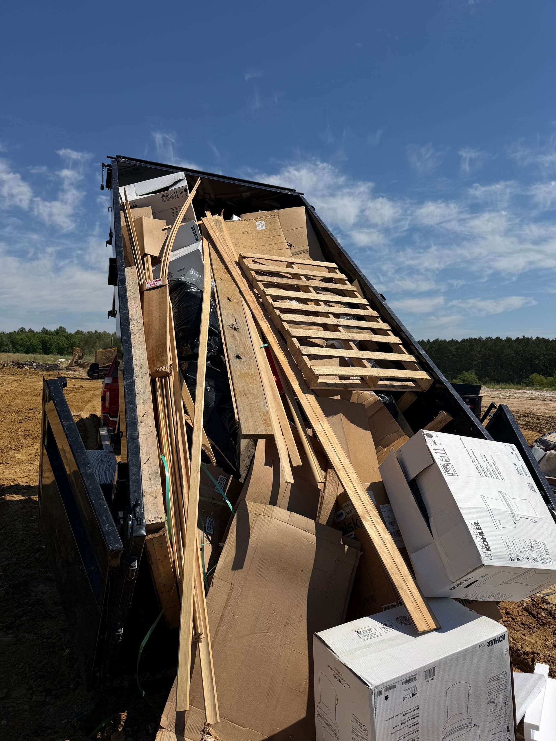 Collapsed wooden structure with broken rafters and white blocks in a field under a blue sky