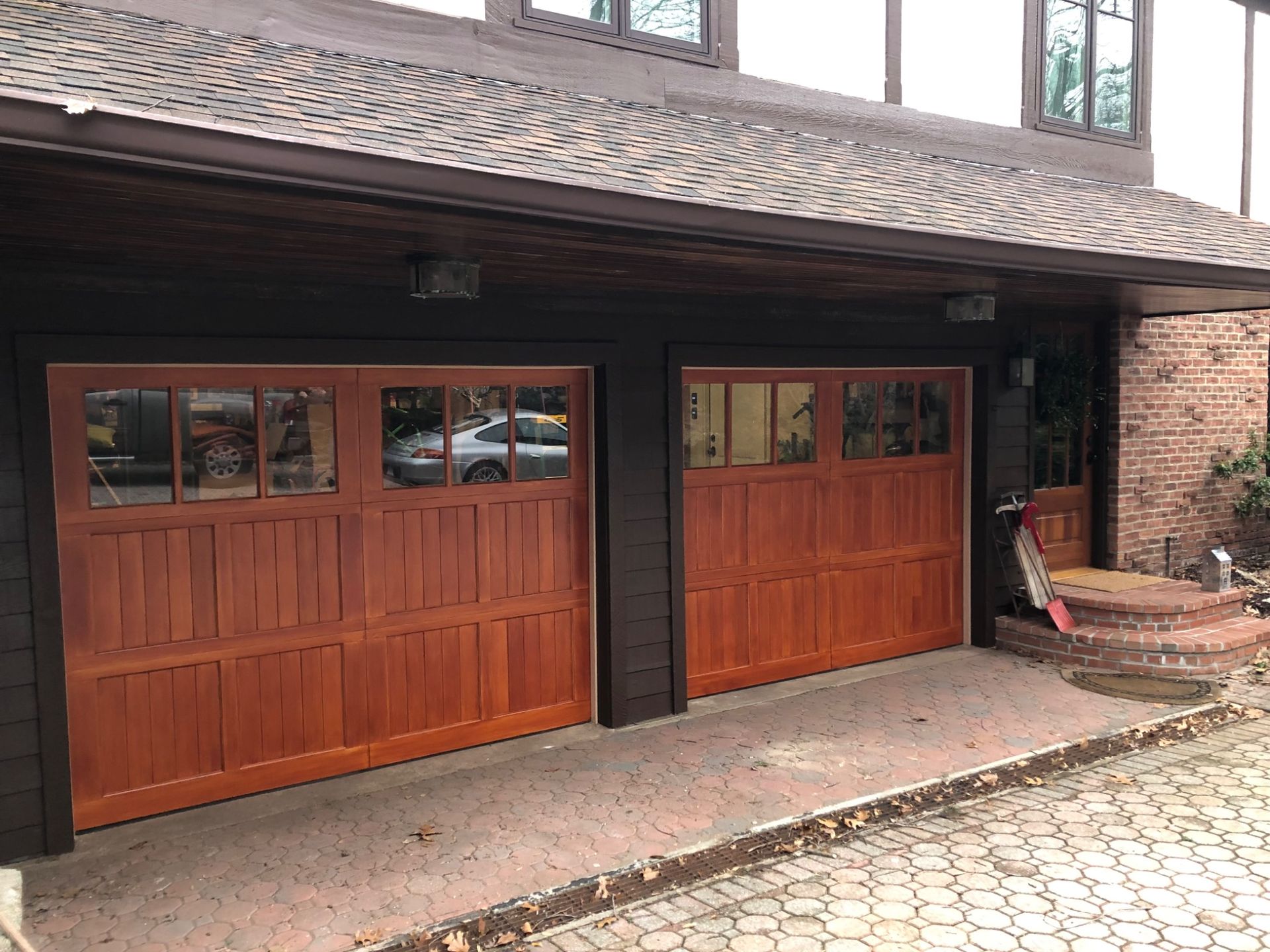 There are two wooden garage doors on the side of a house.