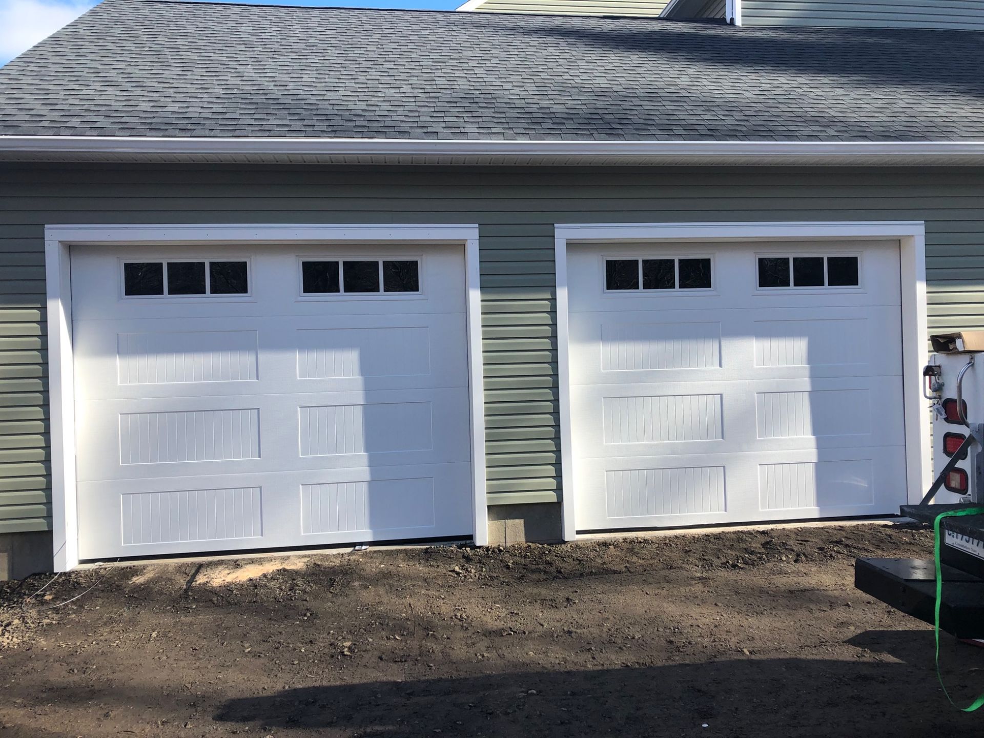 Two white garage doors on the side of a house