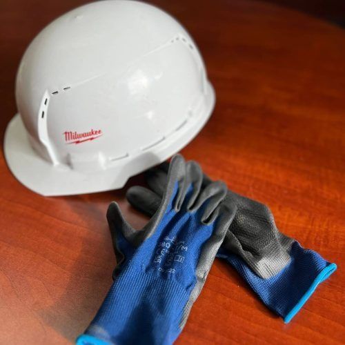 White hard hat and blue work gloves on a wooden table