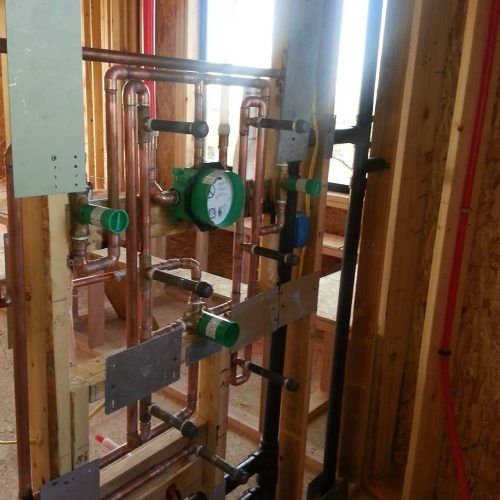 Copper plumbing and gauges installed in an unfinished wall framing interior