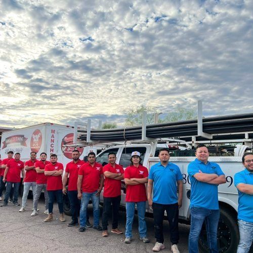 Group of workers in red and blue shirts standing beside a truck under a cloudy sky