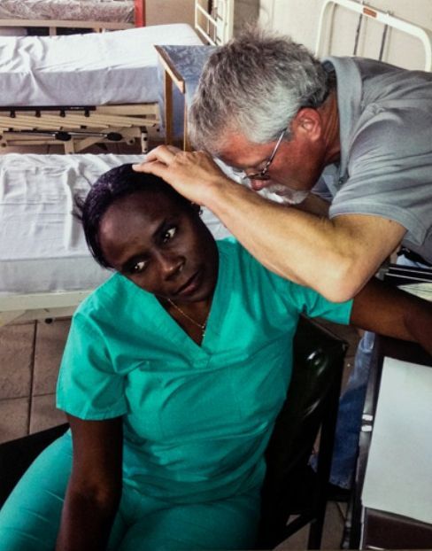 A doctor examines a nurse's neck in a hospital room
