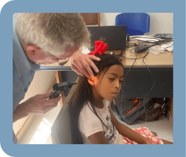 A man is examining a little girl 's ear with a stethoscope.