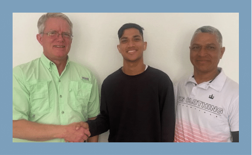 Three men are shaking hands in front of a white wall.