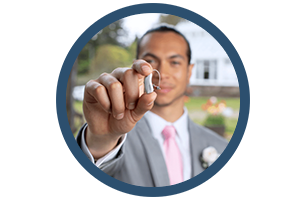 A man in a suit and pink tie is holding a wedding ring