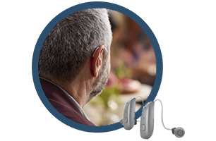 A man wearing a hearing aid is sitting at a table.