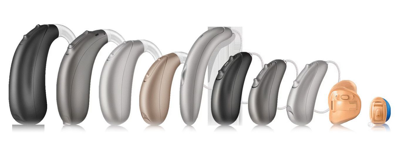 A variety of hearing aids are lined up in a row on a white background.