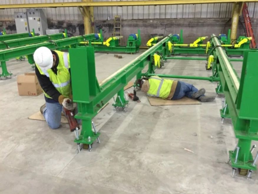 A man is working on a green machine in a factory.