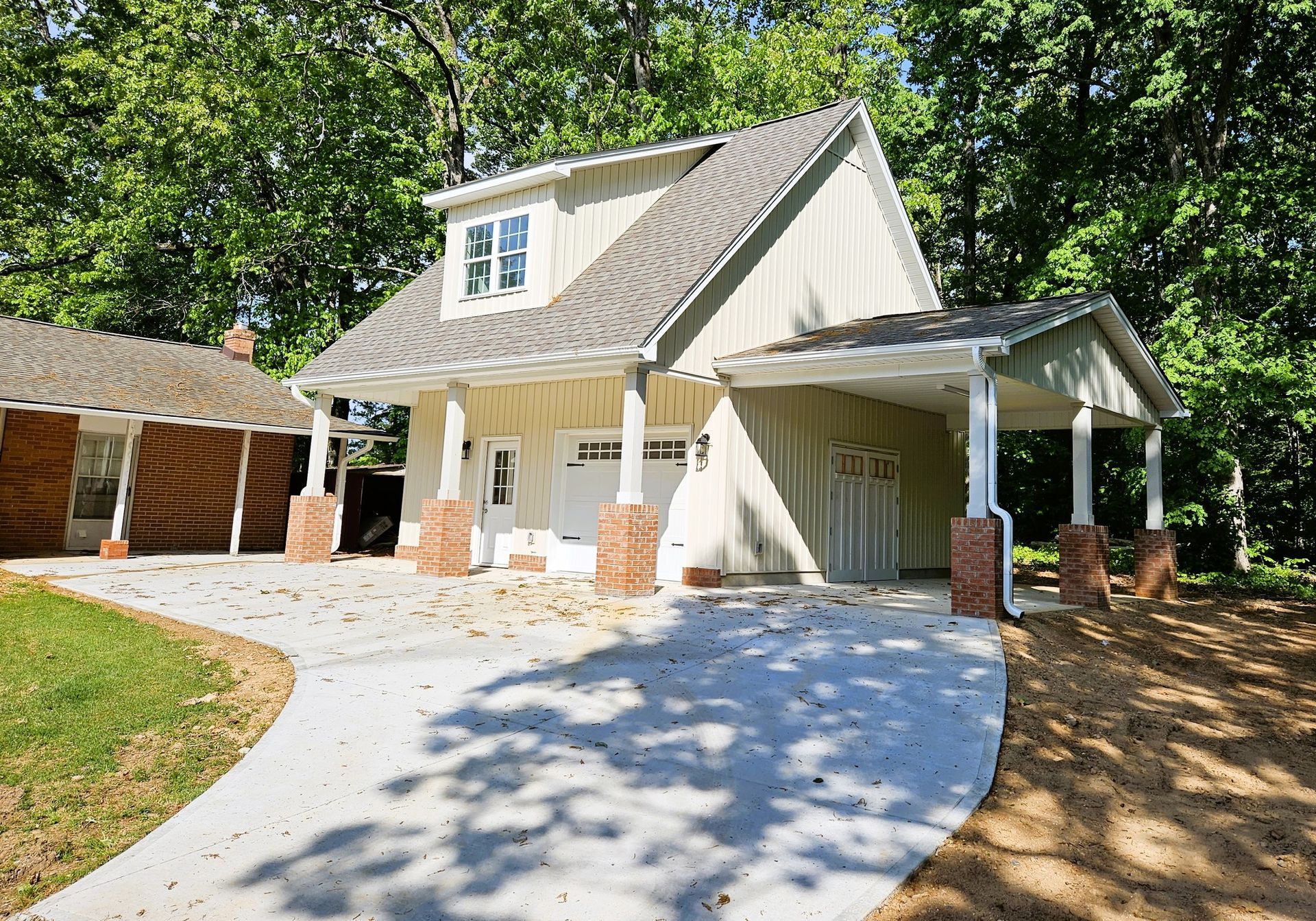 Beige house with attached carport, brick columns, concrete driveway, and green lawn.