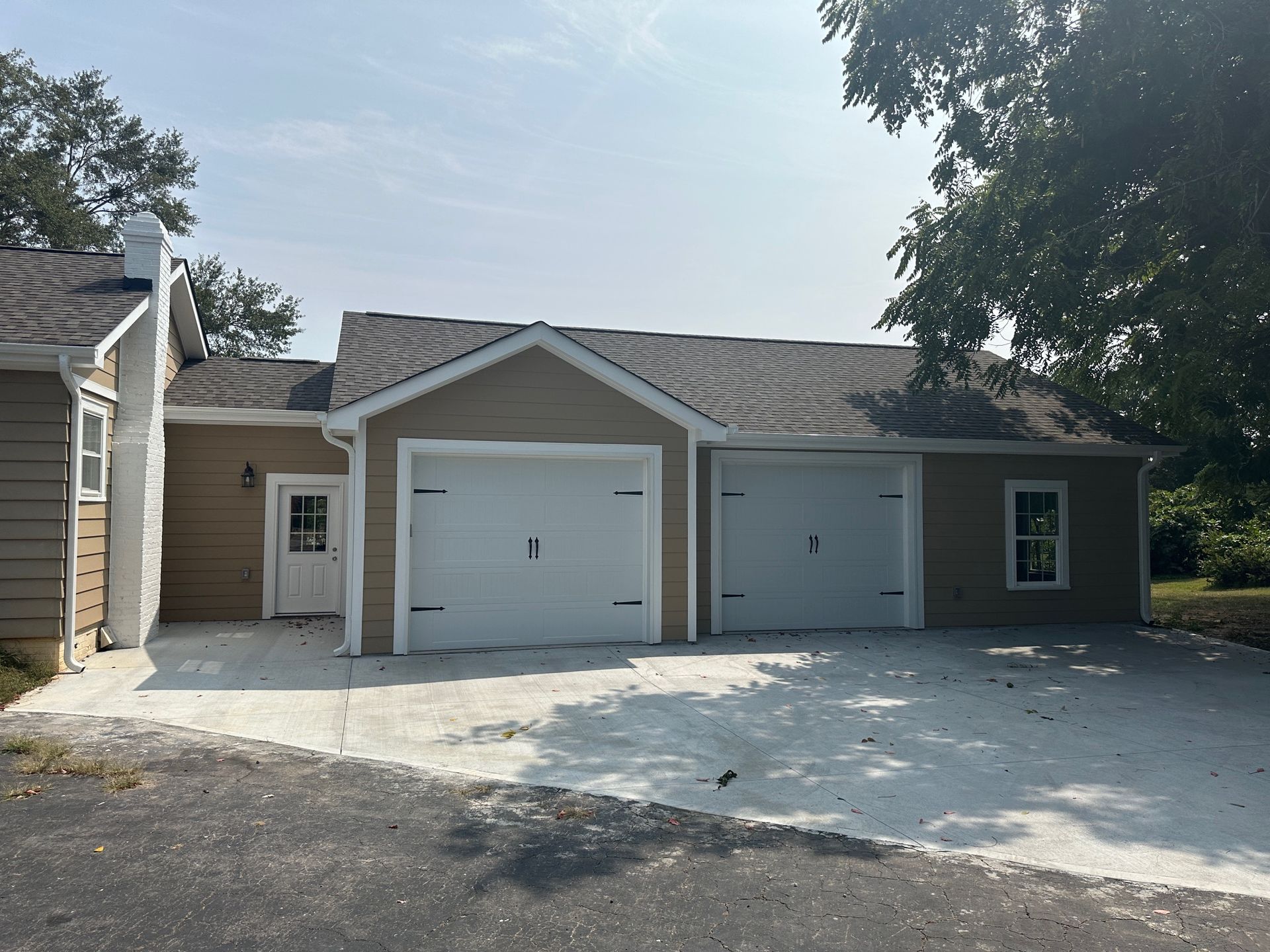 Tan house with two garage doors and a concrete driveway.