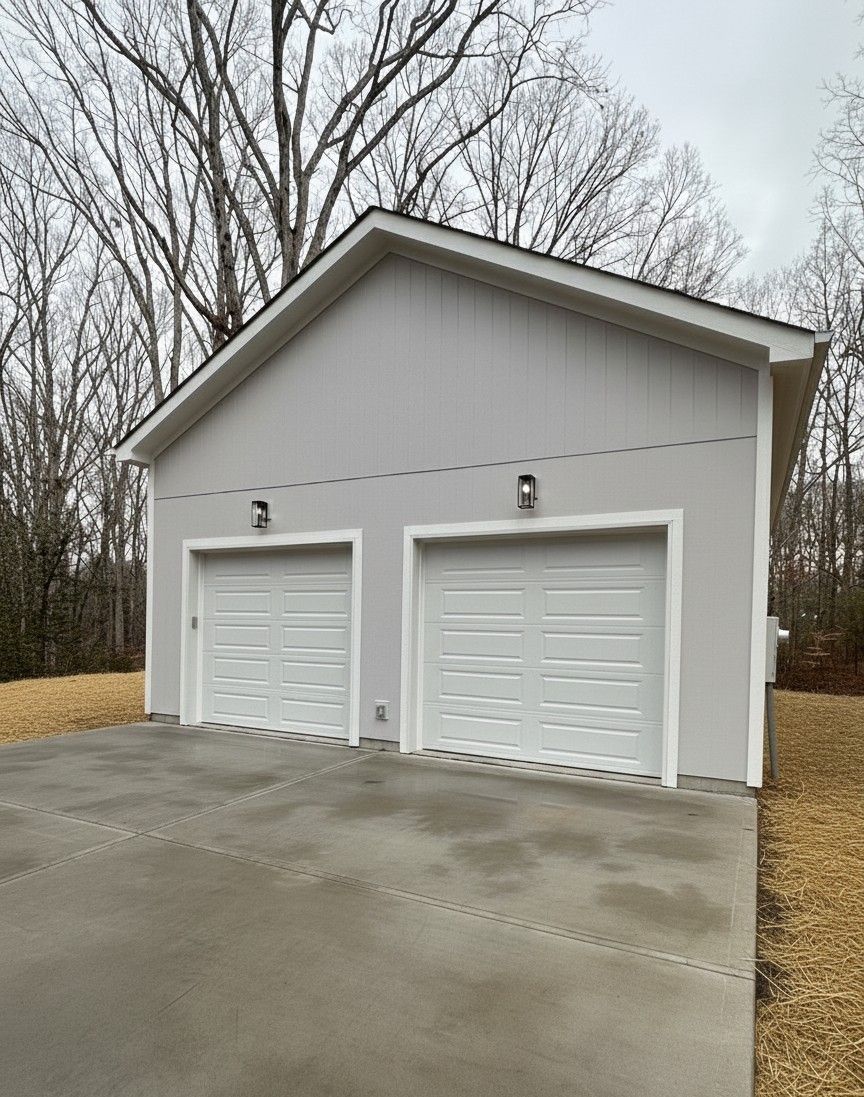 Two-car garage with gray stucco exterior and white garage doors, set on a concrete driveway.