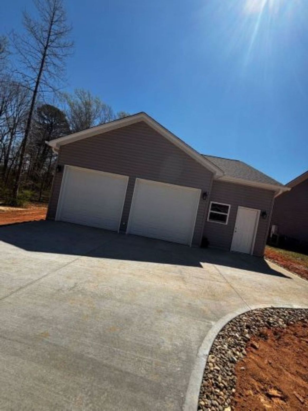 long driveway leading to grey house with two door driveway