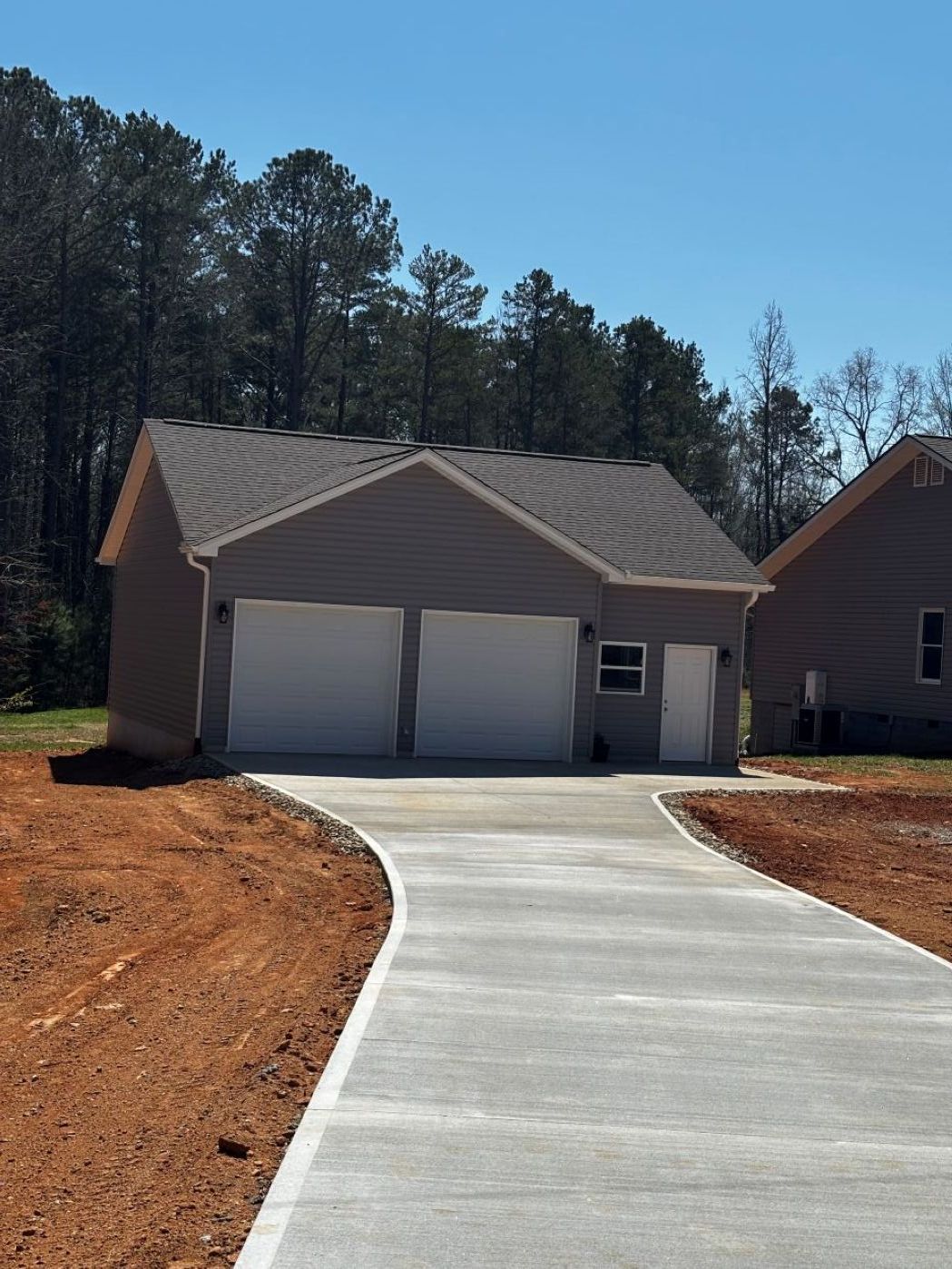 long driveway leading to grey house with two door driveway