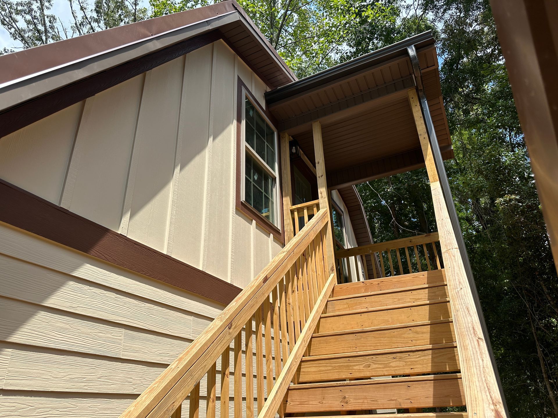 A side view of tan garage with wooden steps and window