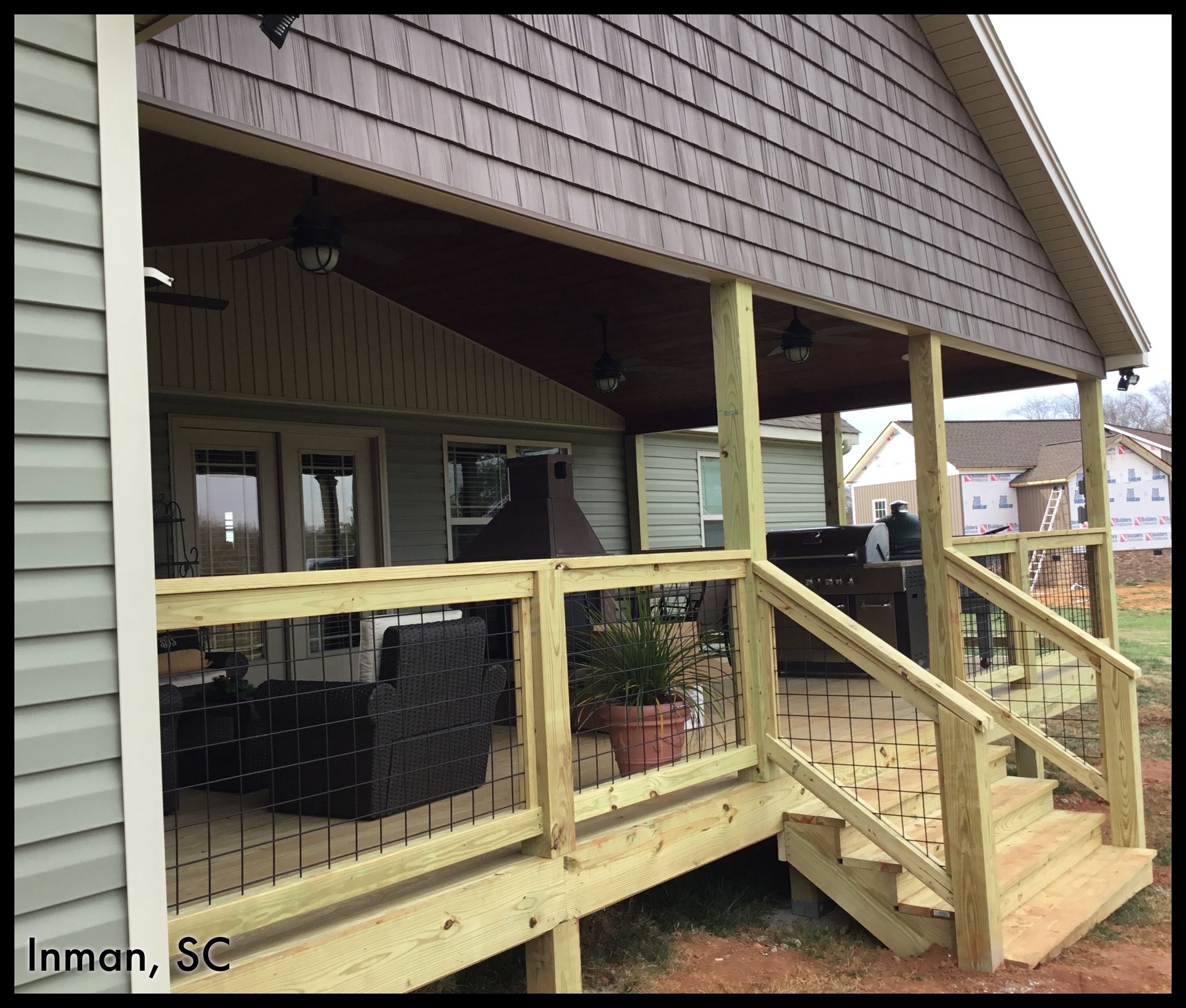 Covered wooden porch with railing, steps, and seating area; Inman, SC.