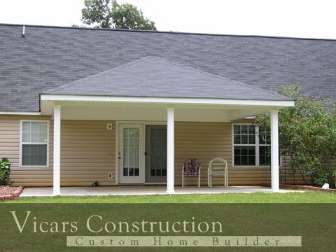 Beige house with attached patio covered by a dark gray roof; two white pillars.
