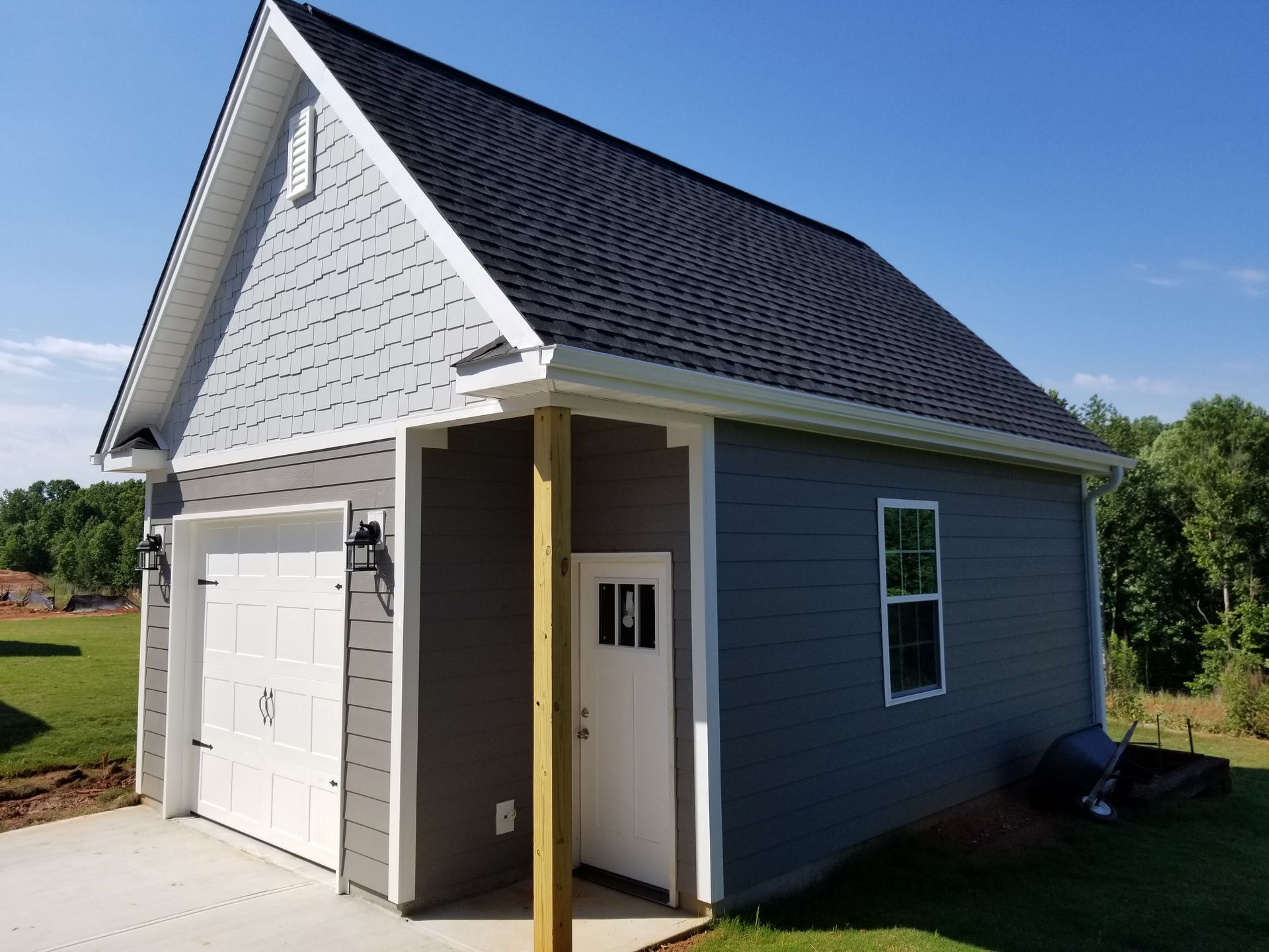 Garage with white door and gray siding against a blue sky.